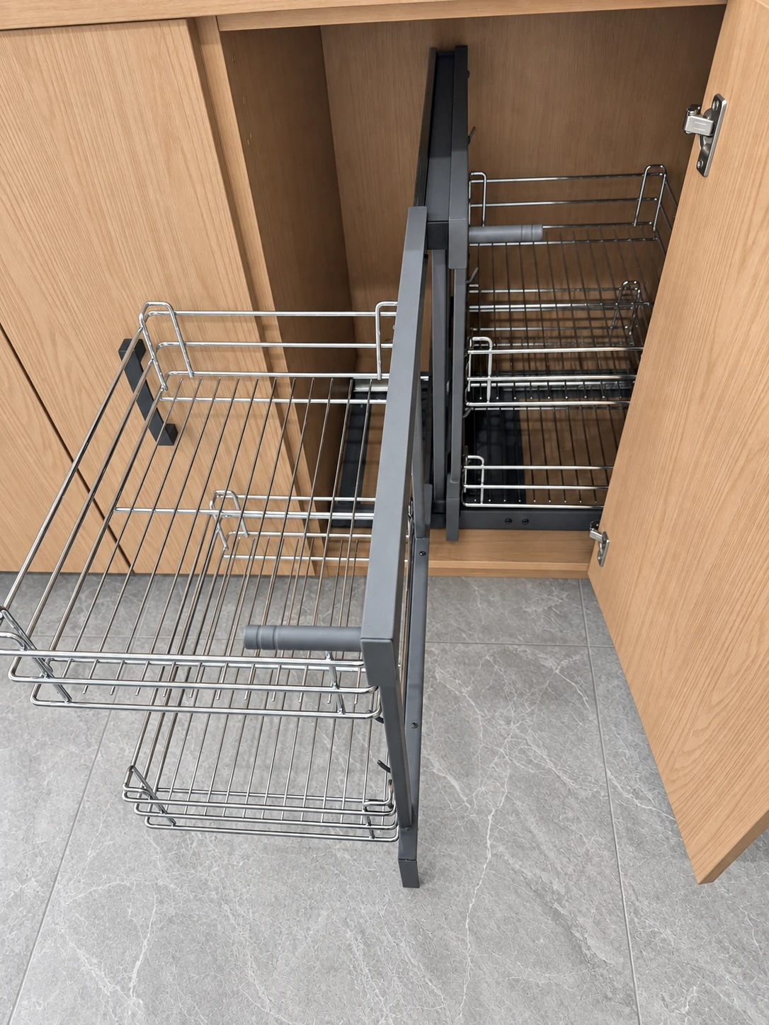 Wire corner cabinet baskets extended beside a central frame in an open cabinet